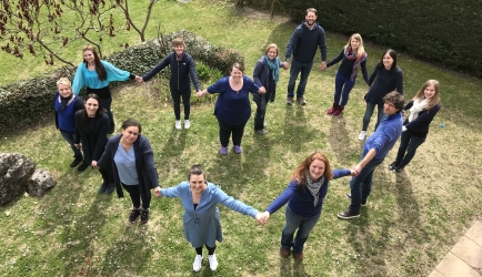 Les professionnels de l'équipe du centre OVA de Monnetier, vêtus de bleu, se tiennent la main et forment un coeur pour la journée de l'autisme