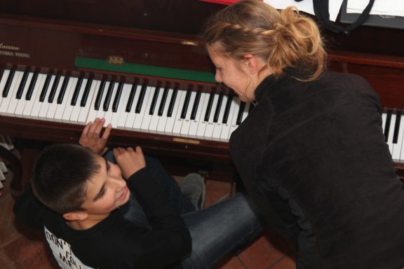 Un jeune adolescent joue du piano avec son éducatrice