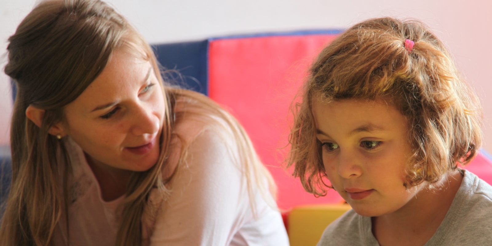 Moment d'échange entre une petite fille blonde et son éducatrice