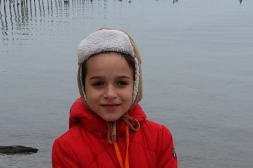 Enfant en veste rouge devant un lac